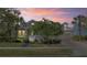 Home exterior at dusk with manicured lawn, mature trees, and landscape lighting, creating a warm and inviting ambiance at 1205 Draycott St, Ormond Beach, FL 32174