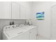 The laundry room has a washer, dryer, sink, white cabinetry, and tiled floors at 1205 Draycott St, Ormond Beach, FL 32174