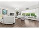 Bright living room with hardwood floors, white furniture, and large windows overlooking the green backyard at 1205 Draycott St, Ormond Beach, FL 32174