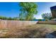 Wide shot of the large backyard featuring a wood fence, grass and trees at 1304 Genmar St, Daytona Beach, FL 32117