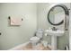 Well-lit half bathroom featuring a pedestal sink, modern toilet, and decorative mirror at 1450 Shady Meadow Ln, Deland, FL 32724