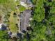Aerial view of a well-maintained house with a dark roof surrounded by lush green trees at 1490 Kettledrum Trl, Enterprise, FL 32725