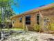 Charming backyard featuring a brick house, arched windows, a small patio, and mature landscaping at 1490 Kettledrum Trl, Enterprise, FL 32725
