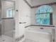 Bright bathroom with a large garden tub under an arched window and glass enclosed shower at 1490 Kettledrum Trl, Enterprise, FL 32725