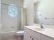 All-white bathroom with shower-tub combo, a unique window, and a vanity with drawers and countertop space at 1490 Kettledrum Trl, Enterprise, FL 32725