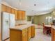 Open concept kitchen with wooden cabinets, an island, and views of the dining and living areas at 1490 Kettledrum Trl, Enterprise, FL 32725
