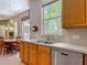 Well-lit kitchen featuring stainless steel appliances, double sink, and wooden cabinets with a view of the dining area at 1490 Kettledrum Trl, Enterprise, FL 32725