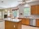 Bright kitchen featuring an island, stainless steel dishwasher, sink, and wooden cabinets at 1490 Kettledrum Trl, Enterprise, FL 32725