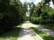 Paved road cutting through a dense, green, tree-lined neighborhood, offering peace and privacy at 1490 Kettledrum Trl, Enterprise, FL 32725