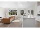 An open concept living room featuring a modern kitchen with stainless steel appliances, a leather sofa, and large bright windows at 1540 Park Forest Blvd, Mount Dora, FL 32757