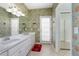 Bathroom boasts double sinks with white cabinets and vintage-style floral wallpaper at 1628 Bent Oaks Blvd, Deland, FL 32724