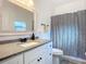 Bathroom featuring a granite countertop, white cabinets, framed mirror, and a decorative shower curtain at 1820 18Th St, Orange City, FL 32763