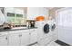 Well-lit laundry area with white cabinets, sink, and newer washer and dryer units near a convenient door at 19 Twin River Dr, Ormond Beach, FL 32174