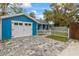 Detached garage featuring a paved driveway, white doors, and a charming white picket fence at 205 Mary Ave, New Smyrna Beach, FL 32168