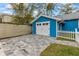 Blue detached garage with white doors and a paved driveway, next to a white picket fence at 205 Mary Ave, New Smyrna Beach, FL 32168
