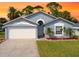 Charming single-story home featuring a manicured lawn, two-car garage, and tropical landscaping at 209 Oak Branch Drive, Edgewater, FL 32141