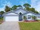 Charming single-story home featuring a well-manicured lawn, two car garage, and inviting front entrance surrounded by lush landscaping at 209 Oak Branch Drive, Edgewater, FL 32141