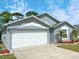 This beautiful home features a two car garage, well manicured lawn, and front entrance with vibrant landscaping at 209 Oak Branch Drive, Edgewater, FL 32141