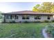Back of home shows large windows that provide natural light, with mature trees and landscaping at 232 Westchester Dr, Deland, FL 32724