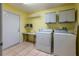 Functional laundry room with a washer, dryer, storage cabinets, and tile floors at 232 Westchester Dr, Deland, FL 32724