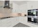 Bright kitchen featuring modern appliances, white cabinets, brick backsplash, and sleek countertops at 29127 Old E Ml, Tavares, FL 32778