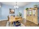 Dining area with wood table, upholstered chairs, wooden china cabinet, chandelier lighting, and light blue accent wall at 3145 Connemara Dr, Ormond Beach, FL 32174