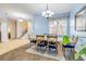 Dining area with a wood table, blue upholstered chairs, staircase, chandelier lighting, and large sunny window at 3145 Connemara Dr, Ormond Beach, FL 32174