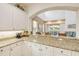 Bright open kitchen with granite countertops and white cabinets, open to dining and living area with a water view at 3145 Connemara Dr, Ormond Beach, FL 32174