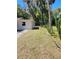 Exterior side-view showcasing the lush backyard with scattered cacti and a neighboring building in the distance at 318 S Massachusetts Ave, Deland, FL 32724