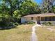 Charming single-story home with a screen door entry and a lush, wooded front yard at 318 S Massachusetts Ave, Deland, FL 32724