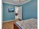 Bedroom with blue walls, wood floors, tv and a door looking into another room with a bookcase at 321 Wade Ave, Deland, FL 32724