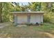 Exterior view of storage shed with a roll-up garage door, surrounded by trees and vegetation at 321 Wade Ave, Deland, FL 32724