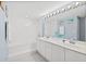 Bright bathroom with a double sink vanity, large mirror with decorative lighting, and a shower/tub combo at 3333 S Atlantic Ave # 2202, Daytona Beach, FL 32118