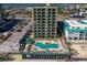 Stunning aerial view of a condo complex with a blue in-ground pool, lounge chairs, and parking at 3647 S Atlantic Ave # 5B, Daytona Beach, FL 32118