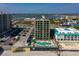 Gorgeous aerial view of a condo with a blue in-ground pool, lounge chairs, and parking area at 3647 S Atlantic Ave # 5B, Daytona Beach, FL 32118