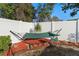 A relaxing hammock hangs in the mulch filled backyard with a white privacy fence at 3825 Arborvitae Way, Deland, FL 32724