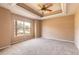 Bedroom with tray ceiling, fan, carpet flooring, and large window overlooking neighborhood at 69 Grey Dapple Way, Ormond Beach, FL 32174
