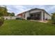 Manicured backyard featuring a lush lawn, screened patio, and an outdoor dining set with an umbrella at 9033 Cape Cod Rd, Deland, FL 32724