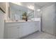 Modern bathroom features a double vanity, a large mirror, and a glass-enclosed shower at 9033 Cape Cod Rd, Deland, FL 32724