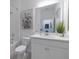 Bright bathroom features a white vanity with countertop, toilet, tiled shower/tub combo, decorative art and a large mirror at 9033 Cape Cod Rd, Deland, FL 32724