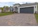 Expansive brick driveway leading to a home with a well-kept lawn, and a two-car garage at 9033 Cape Cod Rd, Deland, FL 32724