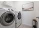 Well-equipped laundry room with modern washer and dryer, overhead shelving for supplies, and a decorative wall art piece at 9033 Cape Cod Rd, Deland, FL 32724