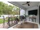 A screened-in outdoor patio featuring a dining table, ceiling fan, TV, and a BBQ grill at 9033 Cape Cod Rd, Deland, FL 32724