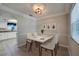 This staged dining room has a modern light fixture, a white table, and a view into the kitchen at 912 Tree Garden Dr, Port Orange, FL 32127