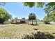 The large fenced backyard features cornhole, grill, patio, and mature trees, perfect for entertainment and recreation at 10 Lilac Dr, Debary, FL 32713