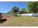 Expansive backyard featuring a white fence, patio, a grill, cornhole game, and mature trees, ideal for outdoor activities at 10 Lilac Dr, Debary, FL 32713