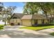 Exterior view of a tan home, showing the driveway, garage, and well-maintained lawn with mature trees at 1227 Baypoint Ct, Longwood, FL 32750