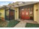 Inviting front entrance with a red double door, sidelights, and a decorative pergola with garden at 1227 Baypoint Ct, Longwood, FL 32750