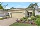 Charming home featuring a beige stucco exterior, brick driveway, manicured landscaping, and a two-car garage at 1684 Victoria Gardens Dr, Deland, FL 32724
