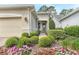 Inviting entrance adorned with lush landscaping and colorful flowers, leading to the charming beige stucco home at 1684 Victoria Gardens Dr, Deland, FL 32724